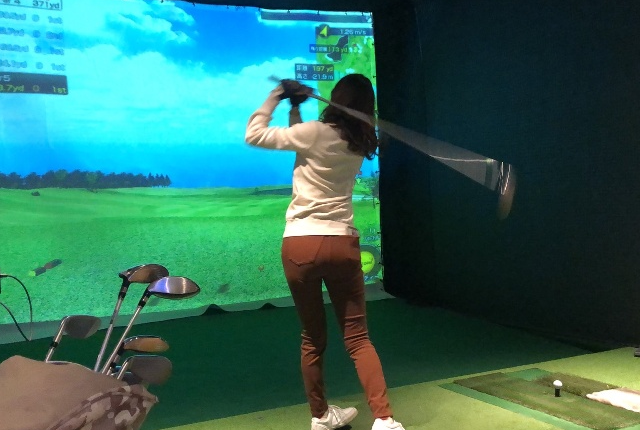 シミュレーションゴルフを楽しむ女性